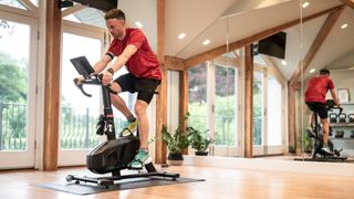 Una persona que monta una bicicleta deportiva Wattbike Proton en interiores