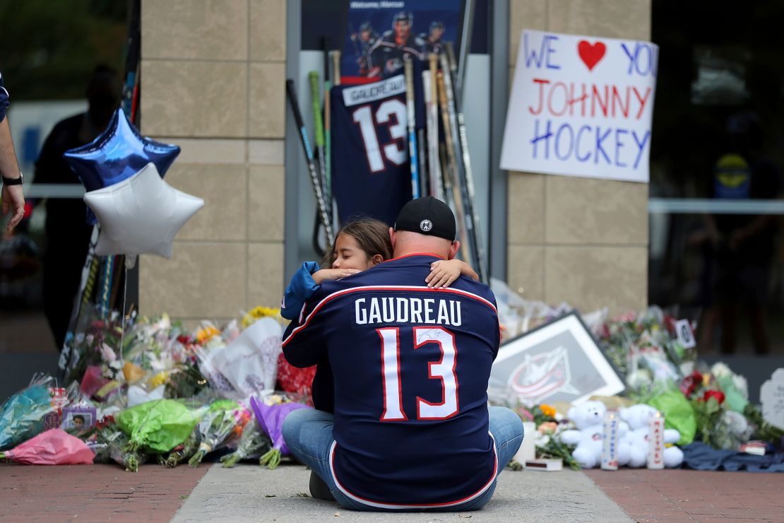 Shilo Rivera está de luto con Hylas Stemen de Columbus el viernes en un monumento improvisado hecho por fanáticos para el jugador de hockey de los Blue Jackets Johnny Gaudreau en Columbus, Ohio.