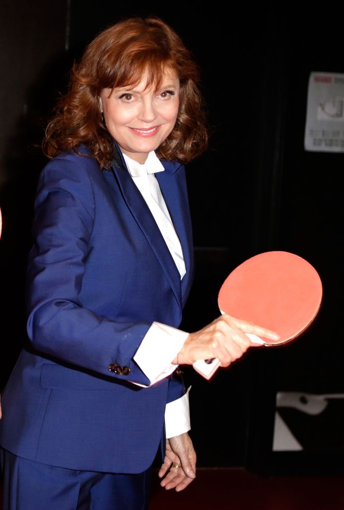 Susan Sarandon, con un disfraz de flota, sosteniendo el estante Ping Tennis