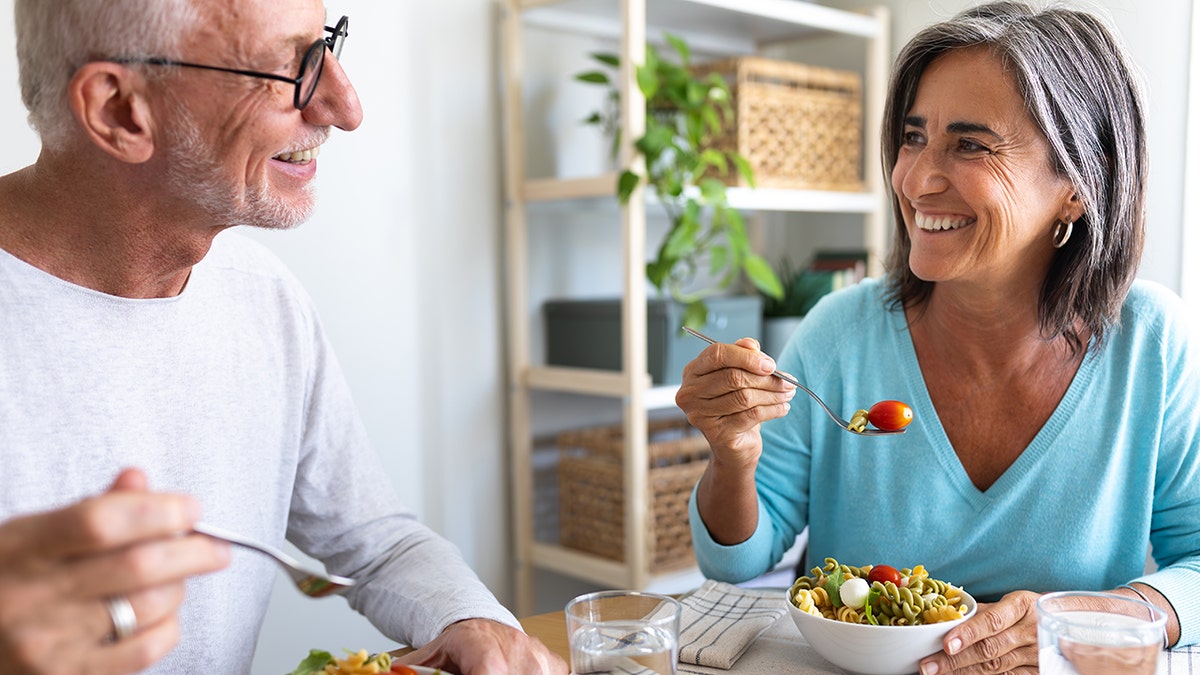 Una gran pareja disfrutando de la ensalada de pasta para cenar