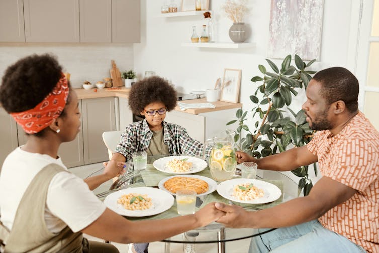 Una familia alrededor de una mesa sosteniendo la mano
