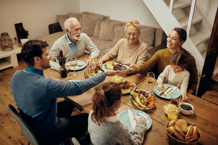 Una familia extendida feliz sentada alrededor de una mesa disfruta comiendo