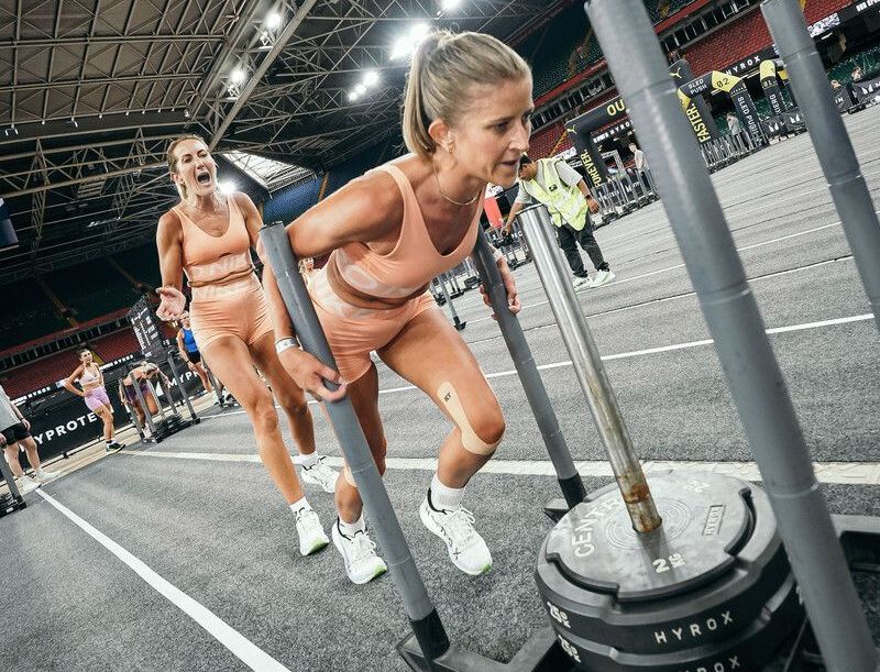 Dos mujeres que acusaron al trineo ponderado durante la competencia Hyrox.
