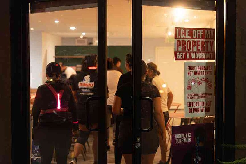 Los miembros del Huntington Park Run Club ingresan a una cafetería emergente construida en una galería de arte en Huntington Park, California, el 24 de septiembre de 2025, como señales de los derechos de los inmigrantes. (AP Photo / Jae C. Hong)