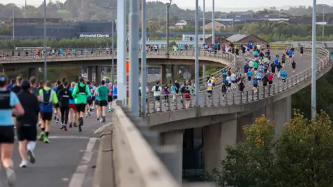 Gran Escocia, un gran grupo deportivo involucrado en una carrera en una carrera en el fondo y una pista de carreras en una carrera en la decoración de la ciudad.