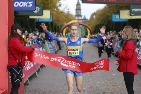 El equipo de trabajo azul rompe la cinta de engranajes de trabajo azul porque gana la media maratón masculina
