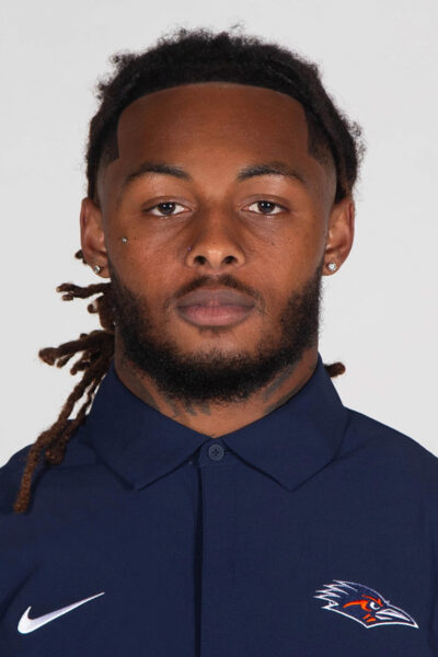 Un hombre viste un polo azul con el logo Nike Swosh y Roadrunner.