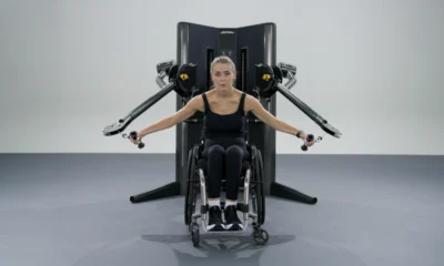 Una mujer en silla de ruedas hace ejercicio con una máquina de cable New Life Fitness