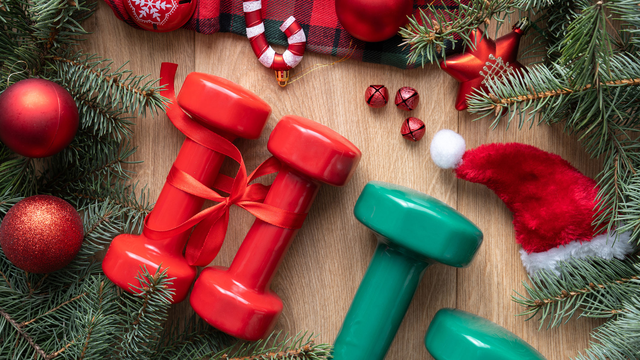 Imagen de dos pares de mancuernas pequeñas entre adornos navideños.
