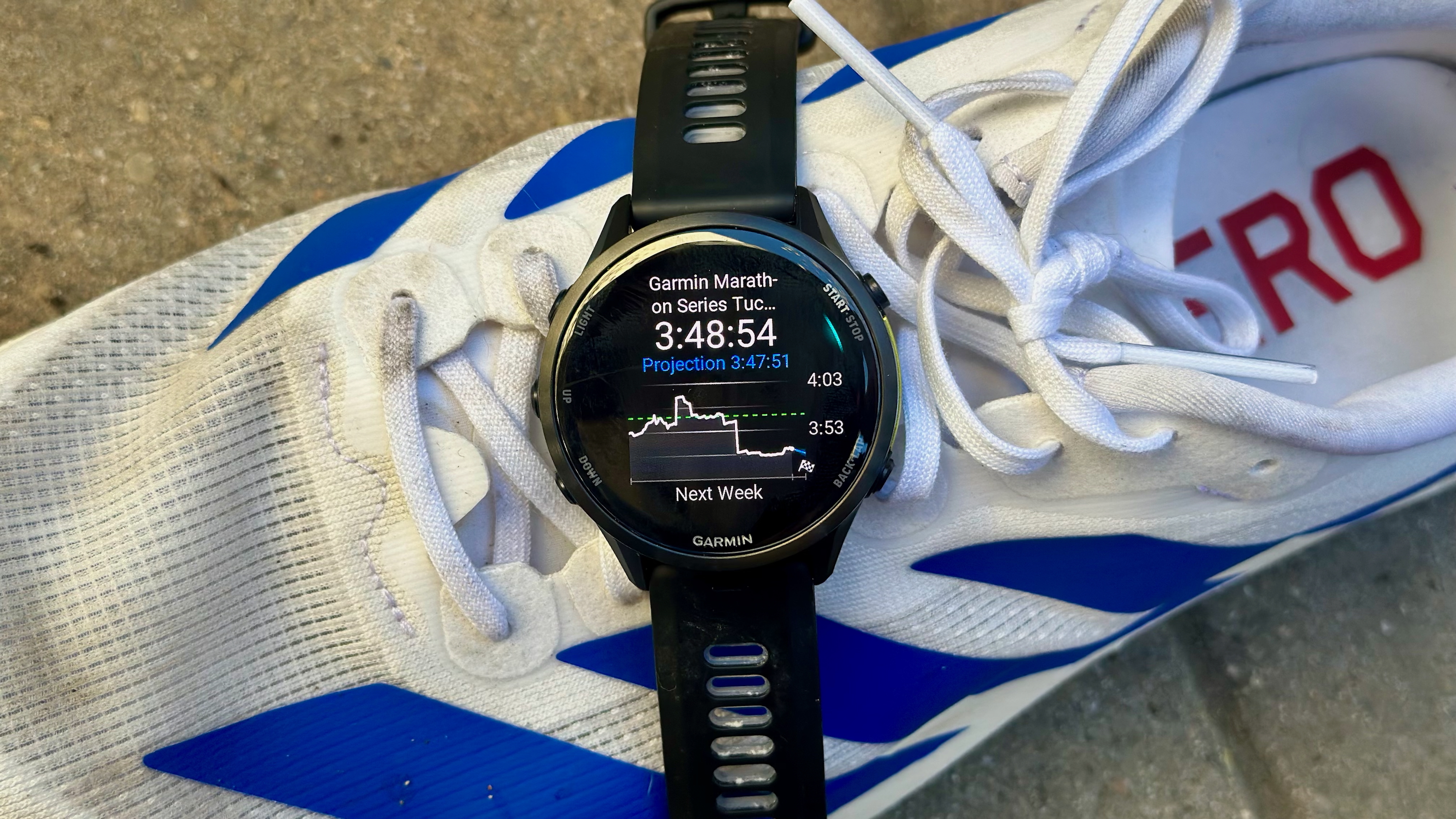 Garmin Forerunner 970 sentado sobre un zapato que muestra un widget de predicción de carrera con mi tiempo de maratón previsto para el Garmin Tucson Marathon