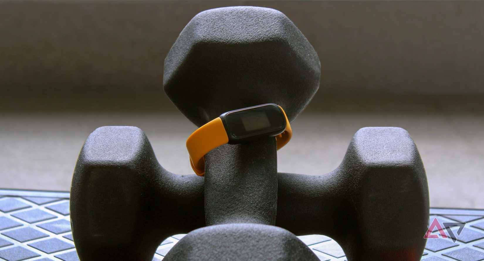 Rastreador de ejercicios Fitbit 3 envuelto alrededor de un mango con mancuernas.