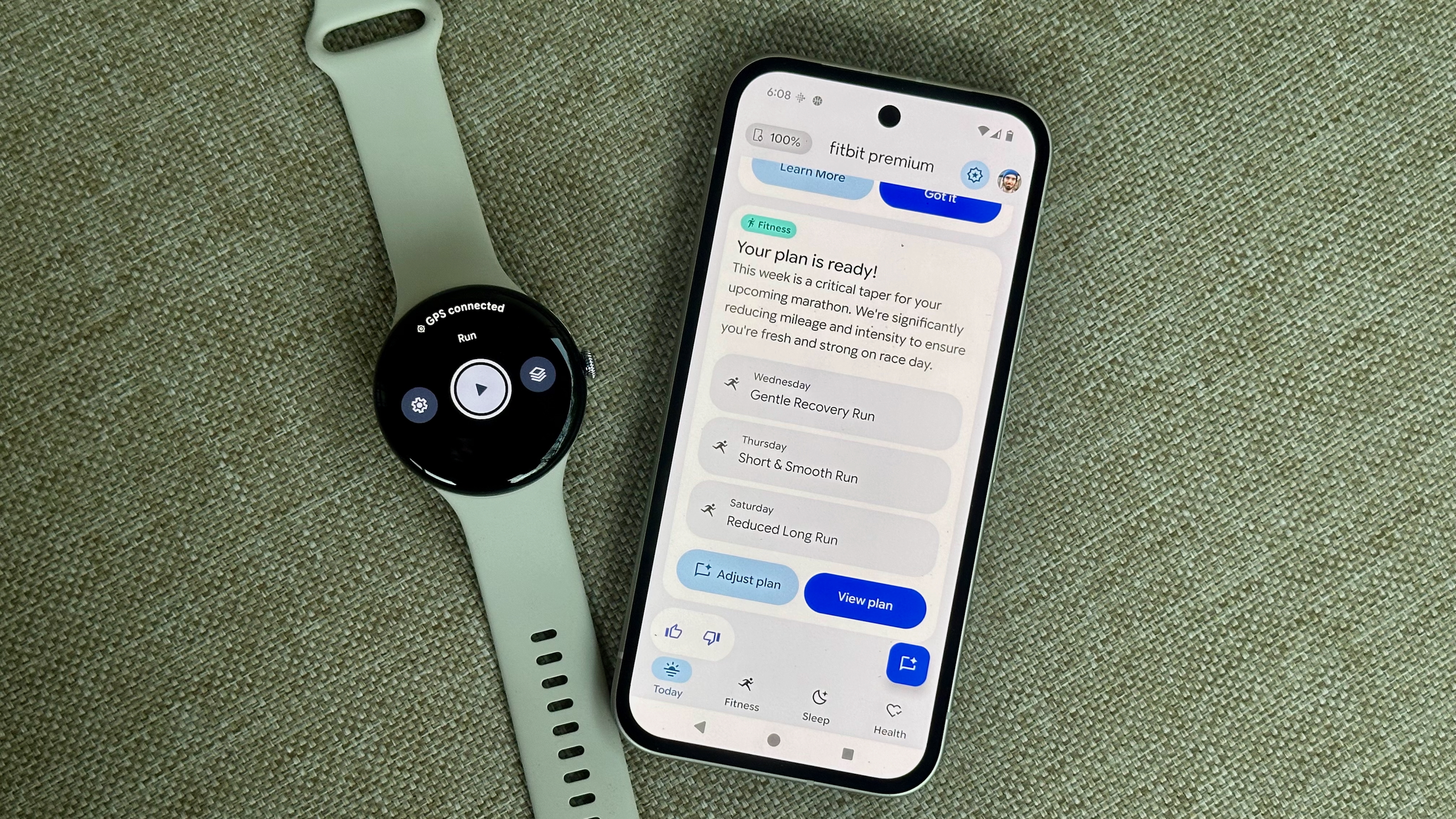 Un píxel 9A con un entrenador de salud premium de fitness en el Google Pixel Watch 4 sentado junto a un Pixel 9A abierto a Fitbit Premium Health Coach Preview 4 muestra un plan de entrenamiento personalizado con tres carreras próximas.