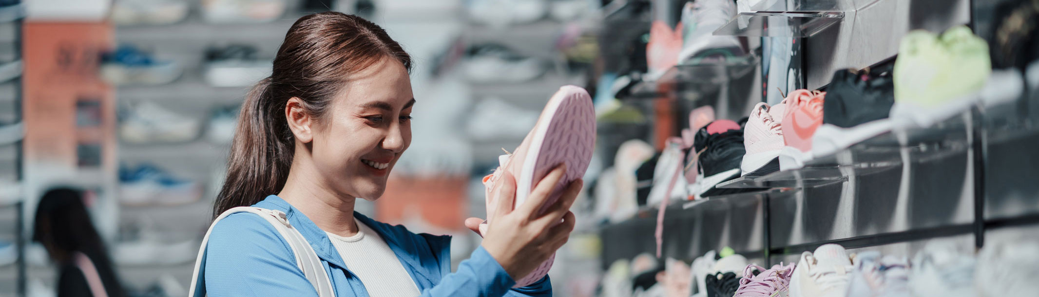 Imagen de una mujer joven comprando zapatillas para correr en una tienda.