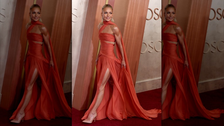 Kelly Ripa camina con un vestido naranja quemado con una abertura alta.
