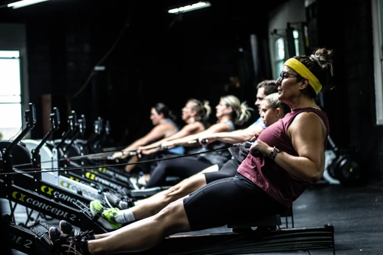 Personas en máquinas de remo en Mecca Fitness
